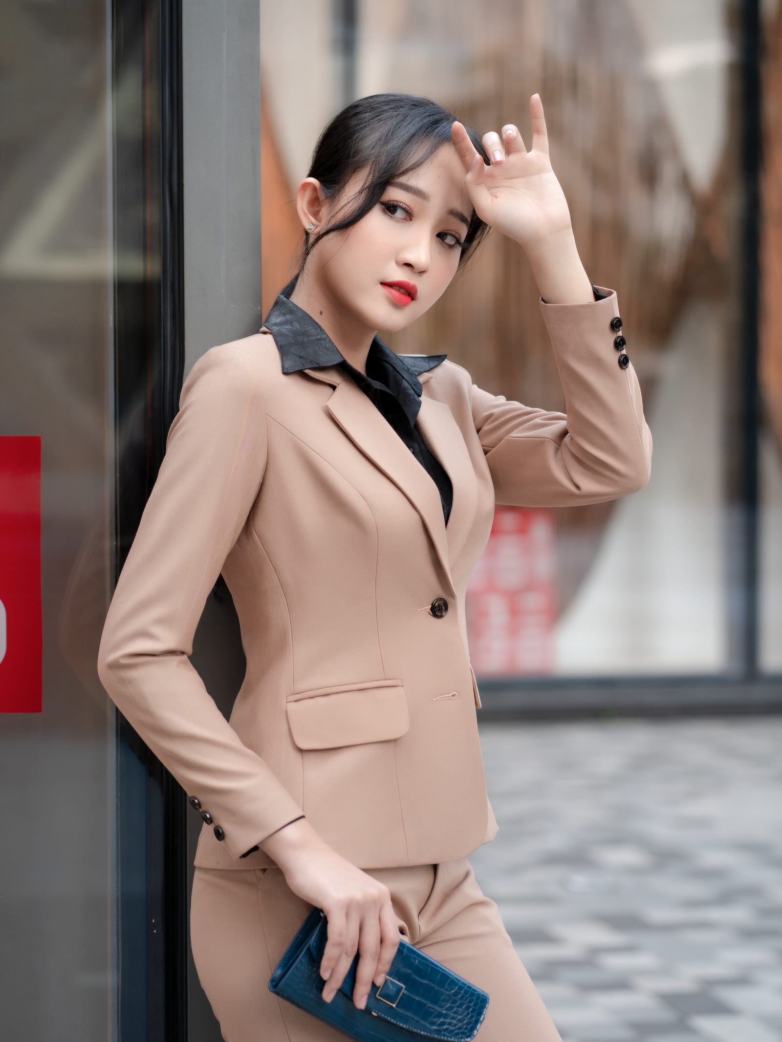 身着米色西装套装的亚洲女性站在街边橱窗前