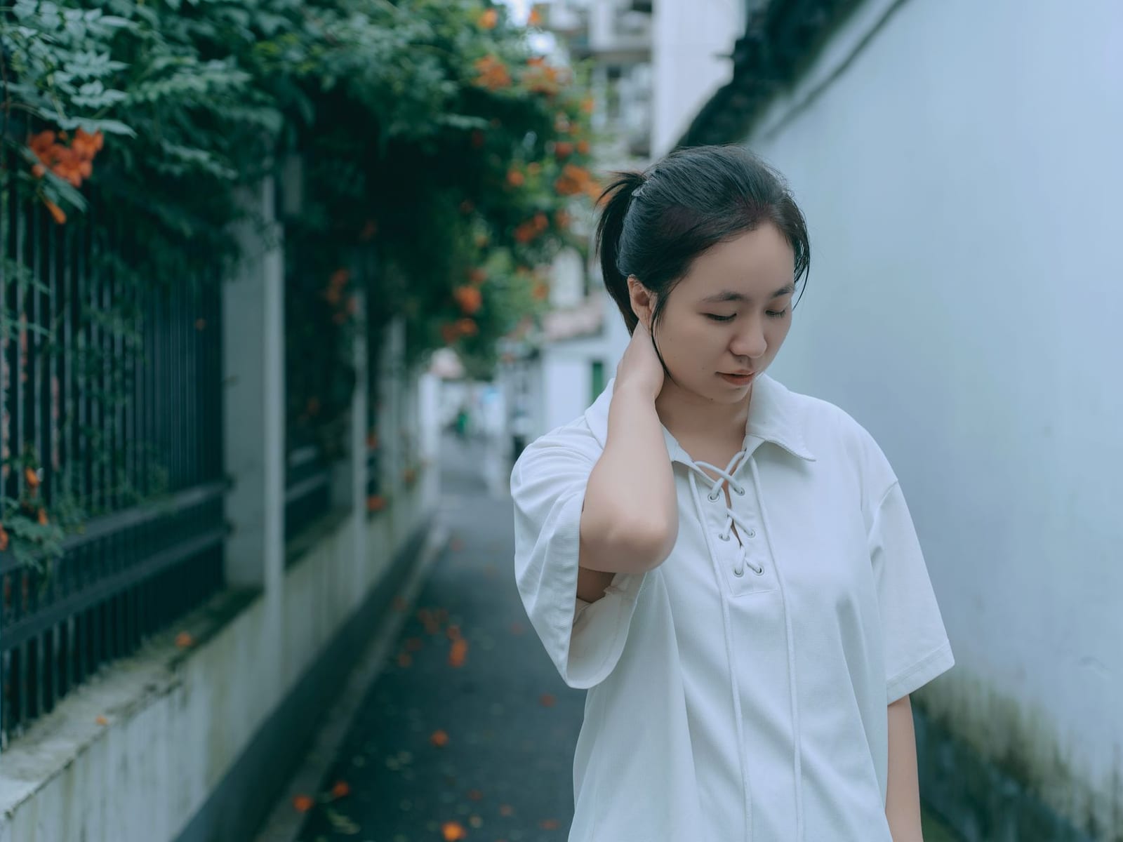 白墙小巷中身着白衬衫的女性